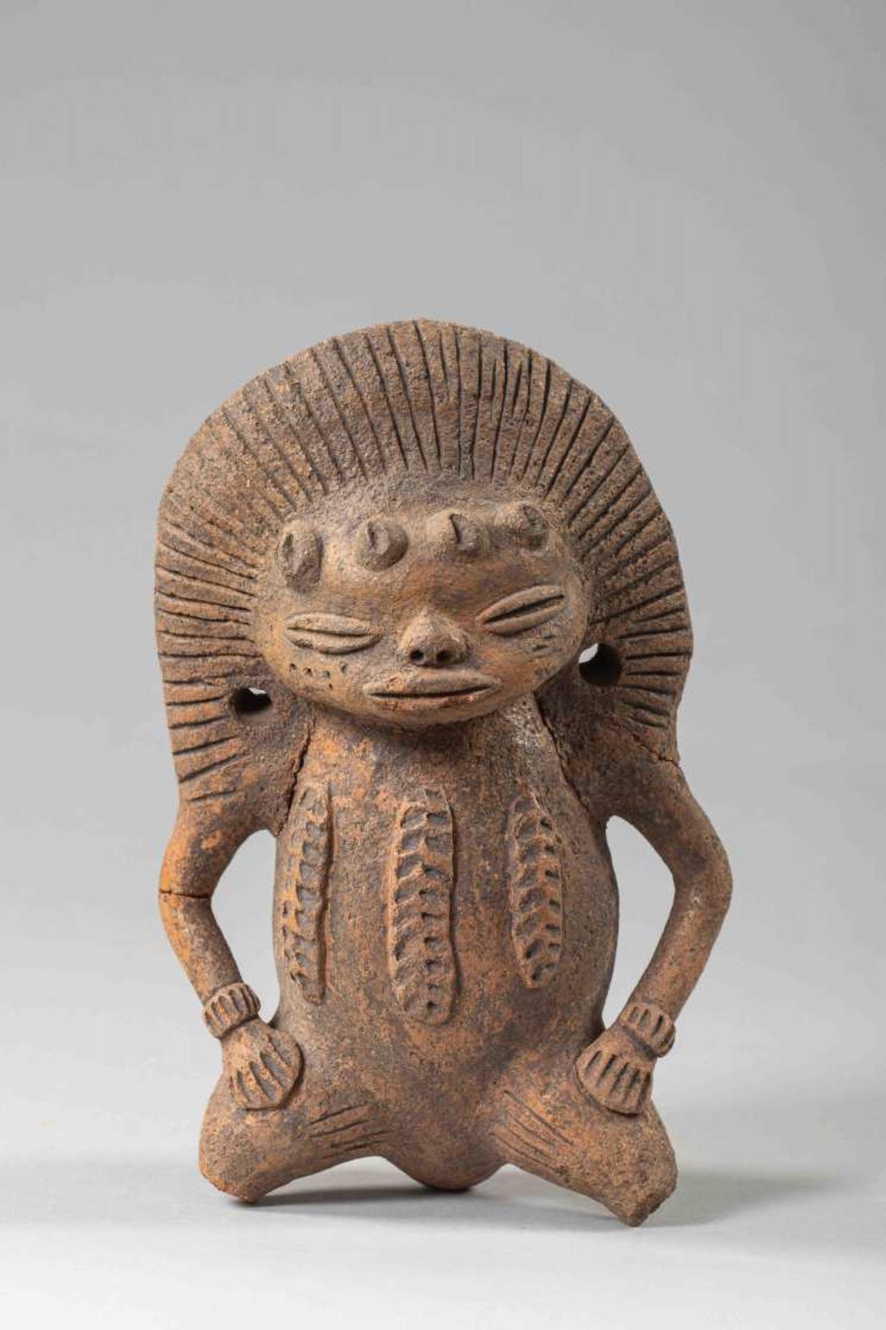 Personnage agenouillé - ColombieEn terre cuite, paré d'une coiffe rayonnante et d'un pectoral à