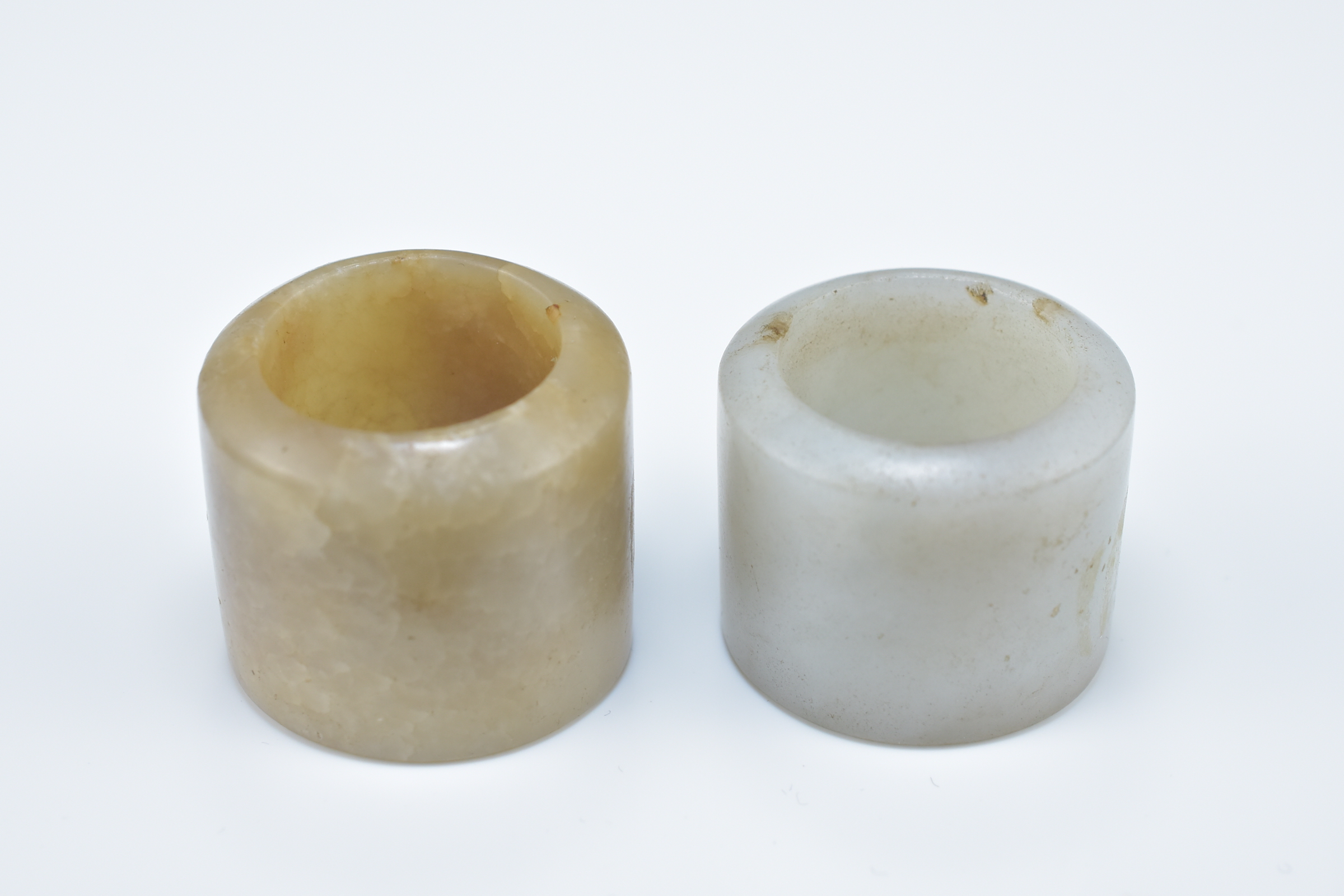 Two Chinese carved jade archers rings. 2.5cm and 3cm length (2)