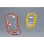 Three dyed coral coloured beaded necklaces together with a long yellow bakelite beaded necklace (4)