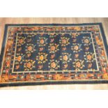A Tibetan / Chinese 19th century blue ground rug woven with orange and tan border decorated with bat