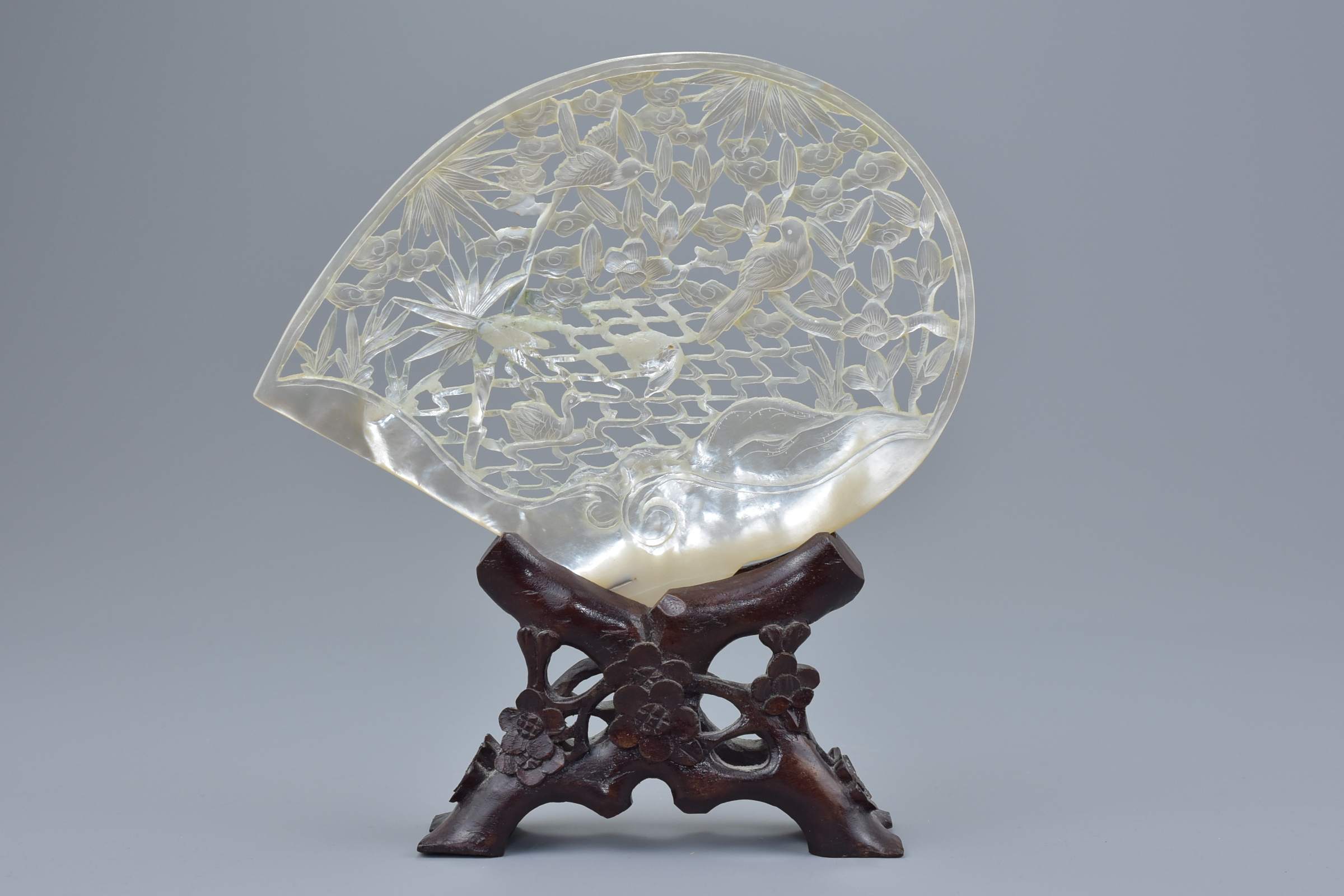 A Chinese vintage mother-of-pearl shell with pierced decoration depicting birds in tree on wooden st