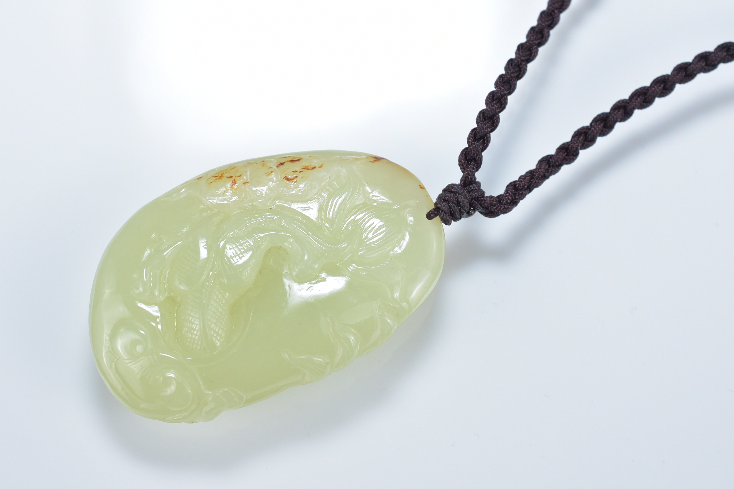 A Chinese celadon and brown jade pendant carved with fish. 5.5cm length - Image 2 of 2