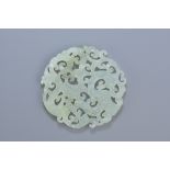 A Chinese carved jade pendant depicting a dragon and phoenix. 6cm diameter