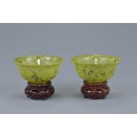 A pair of Chinese bowenite bowls with wooden stands. 10cm diameter (4)