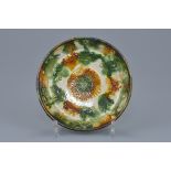 A Chinese Tang dynasty Sancai glazed shallow dish with molded floral decoration. 17cm diameter