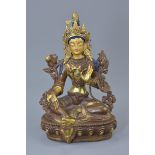 A Tibetan partial gilt bronze Buddha with painted face seated on lotus base. 20.5cm tall