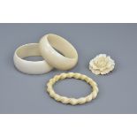 Pair of ivory bangles, together with another ivory bangle with rope twist design, and a carved ivory