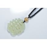 A Chinese celadon jade pendant carved with a 'Shou' character with a bat. 5cm length