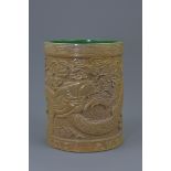 A Chinese porcelain brush pot carved with five claw dragon amongst clouds with green interior and ba