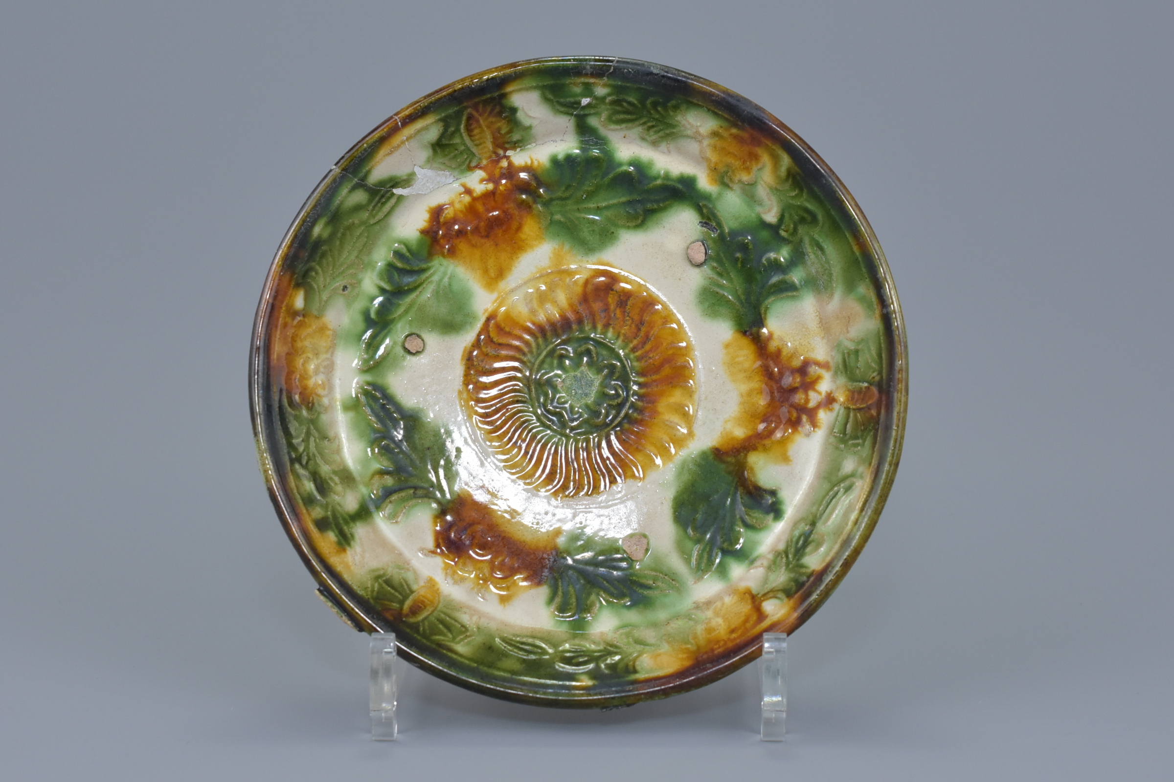 A Chinese Liao dynasty Sancai glazed shallow dish with molded floral decoration. 17cm diameter