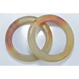 Two Chinese celadon and brown jade bangles. 8.5cm diameter. Inner diameter 6cm.