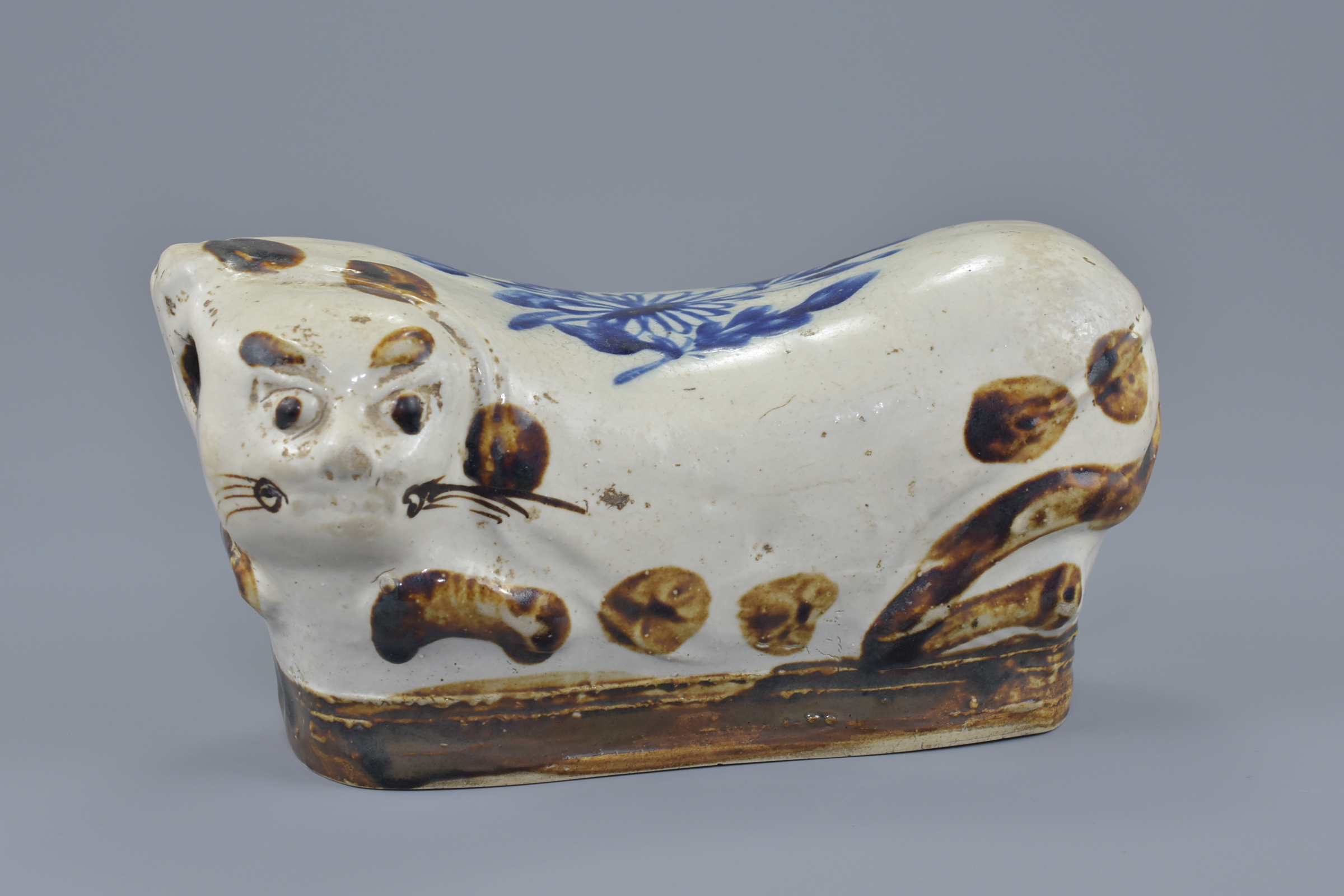 A Chinese 19/20th century glazed and painted pottery pillow in the form of a cat. 25cm length
