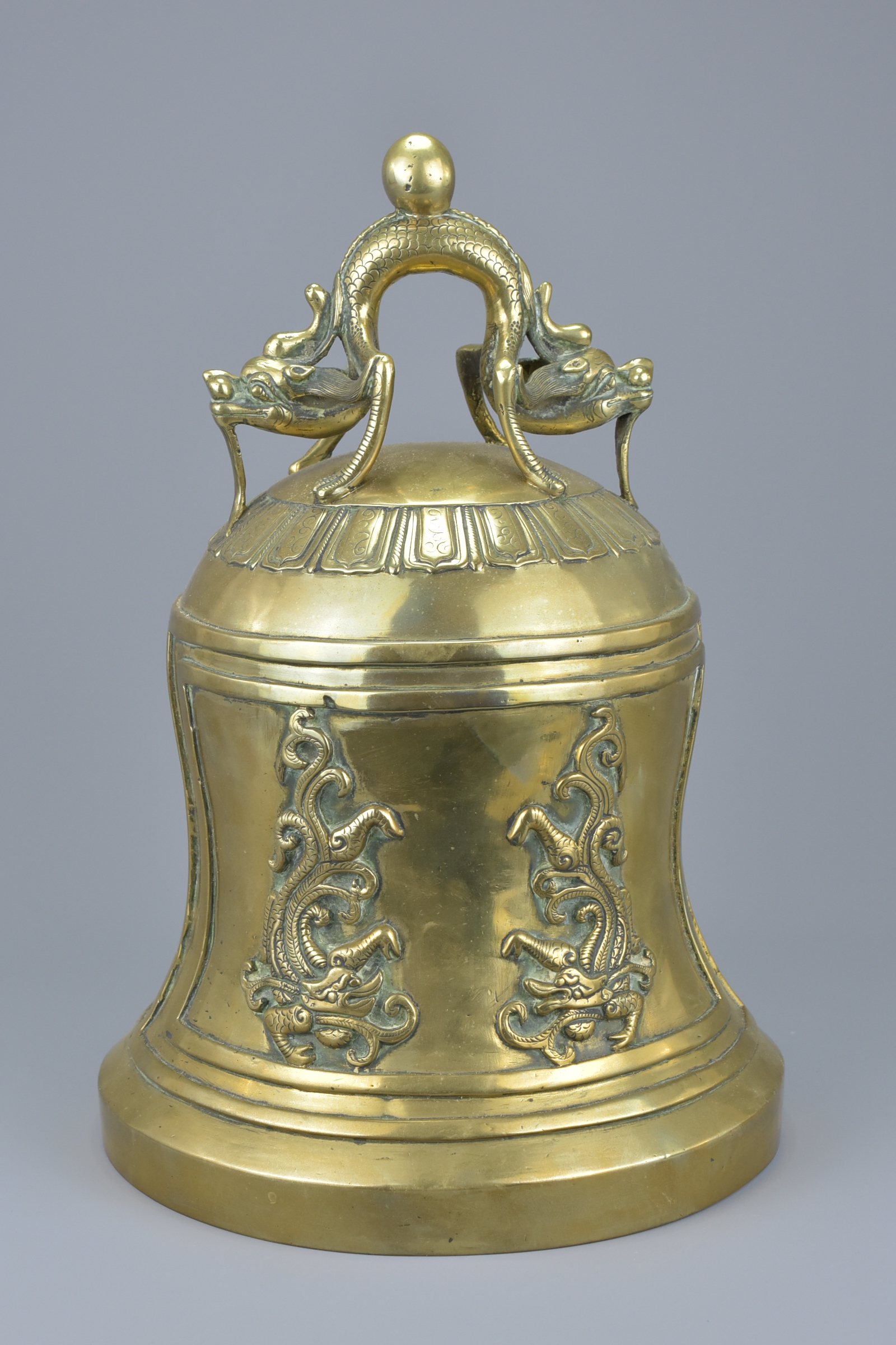A large Chinese polished bronze bell gong mounted with a dragon handle. 33Cm tall