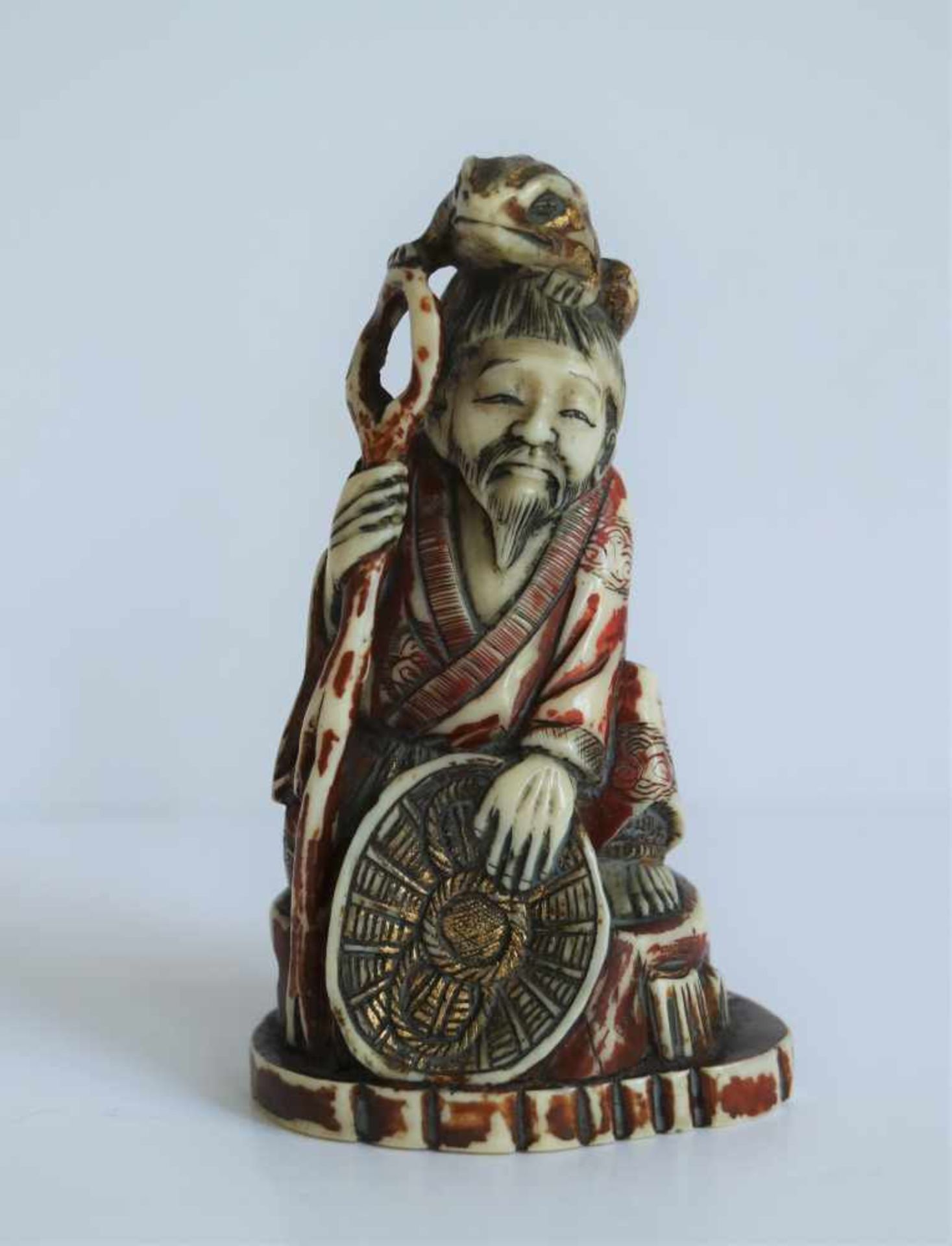 Carved hippopatamus tooth Okimono depicting Gama Sennin with a toad on his head with polychrome.