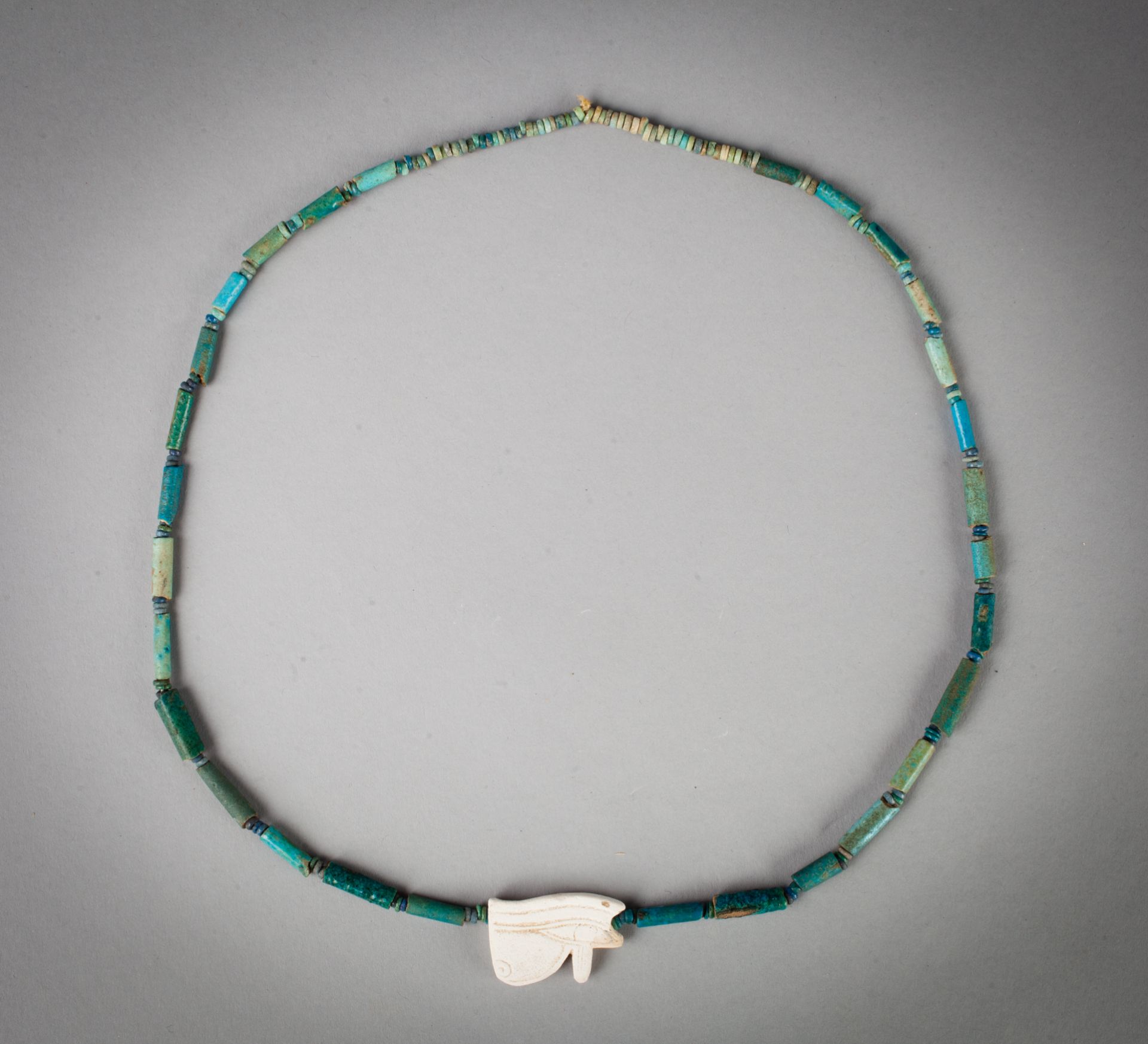 Collier composé de perles tubulaires et annulaires et d'un oeil Oudjat. - Faïence [...]