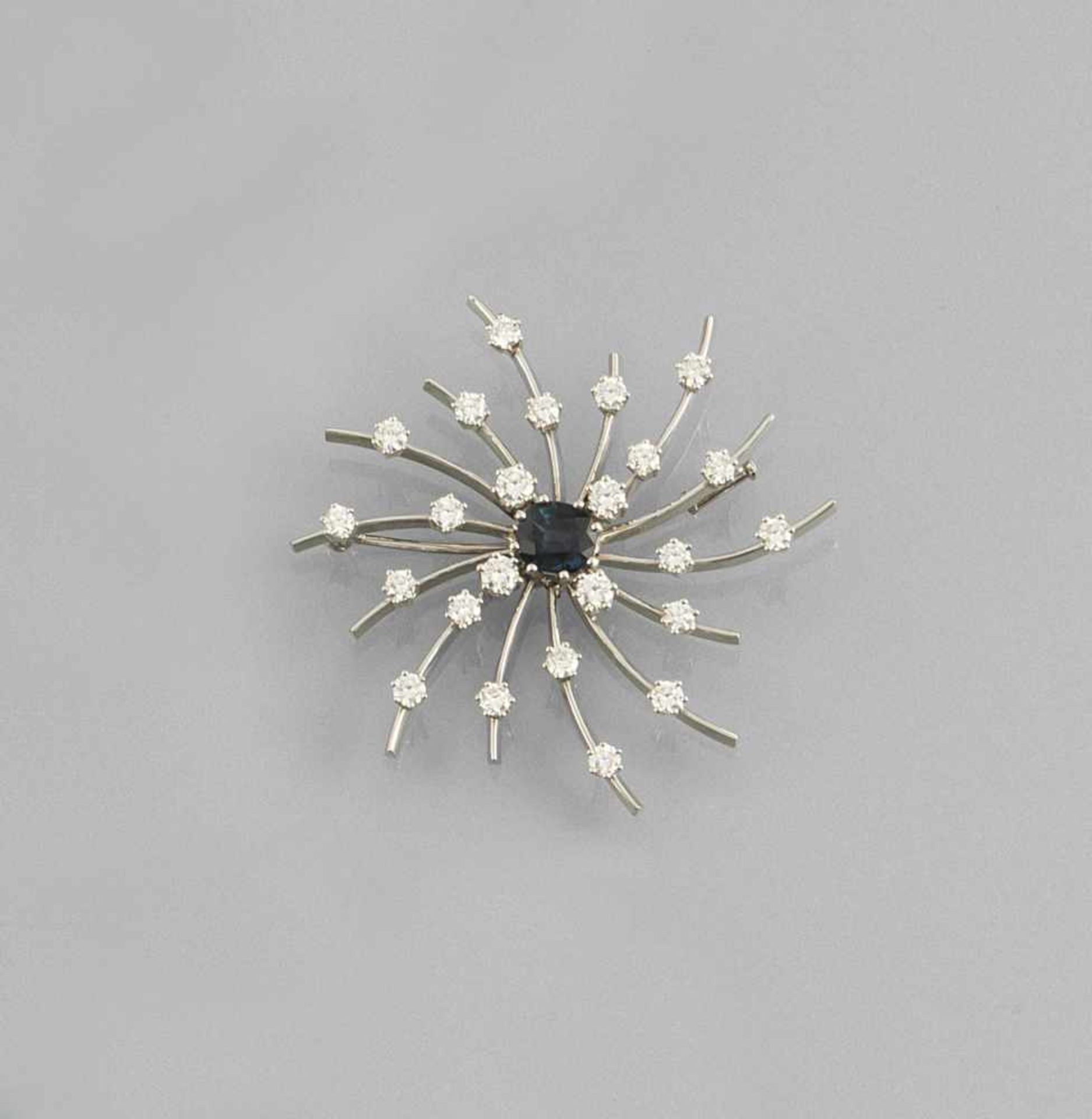 SUN SHAPED WHITE GOLD BROOCH SET WITH an oval cut sapphire of c. 2 ct. and 24 brilliants of tog.c.