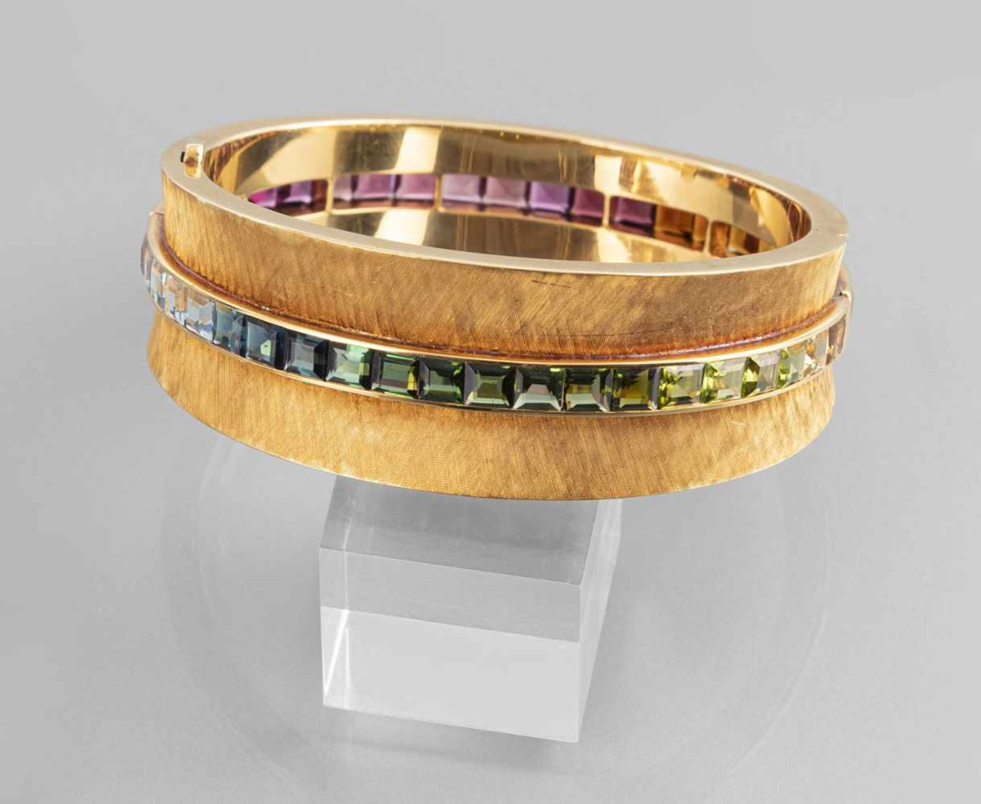 A LARGE 750 YELLOW GOLD BANGLE, set with 43 rectangular cut tourmalines, citrines, aquamarines and