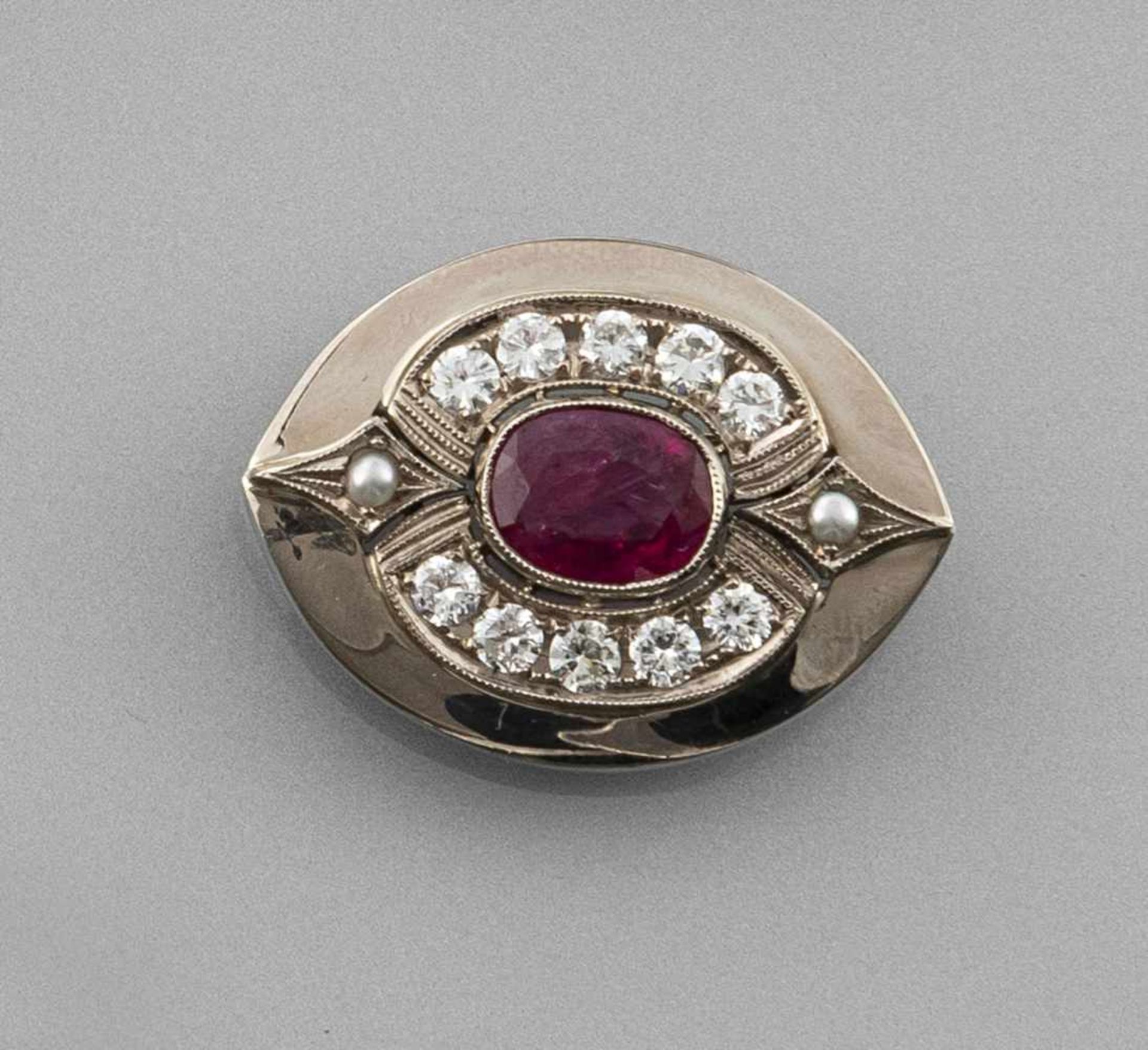 A RUBY AND DIAMOND BROOCH. 750 white gold, oval cut ruby c. 3,2 ct.; 10 brilliants tog.c. 1 ct.