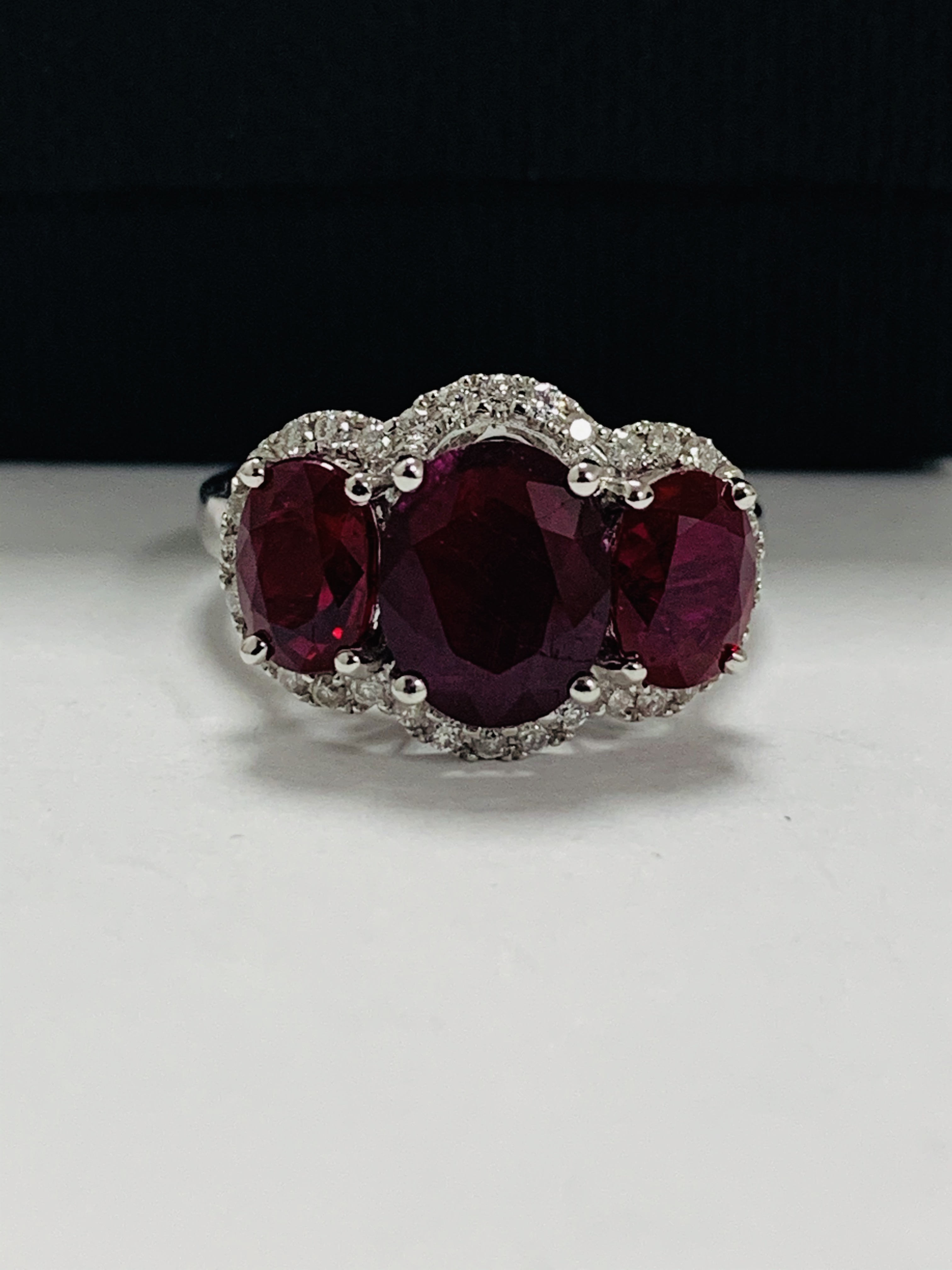 14ct White Gold Ruby and Diamond ring featuring centre, oval cut Ruby (1.67ct), claw set, with 2 ova