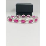 Platinum Ruby and Diamond bracelet featuring, 12 oval cut, pinkish red Rubies (15.19ct TSW), claw se