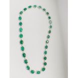 Platinum and Yellow Gold Emerald and Diamond necklace featuring, 29 oval cut, light to deep green Em