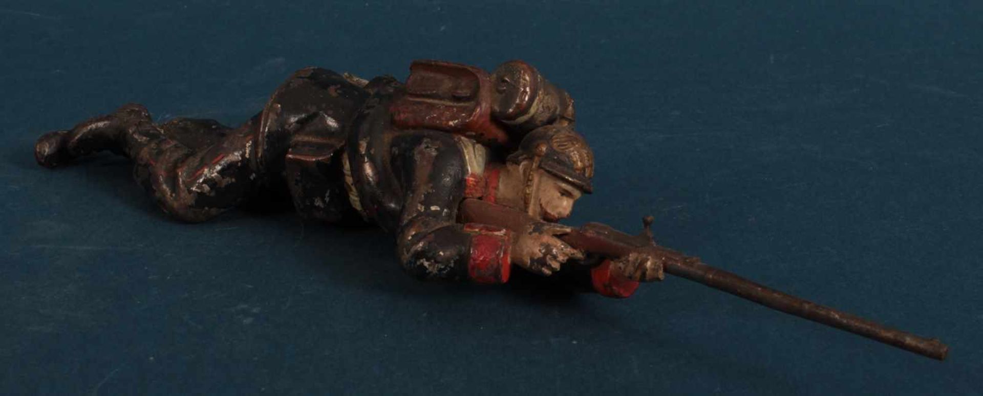 "Kaiserlicher" Soldat, sich anpirschend. Polychrom lackierte Figur, Länge ca. 22 cm; bespielter