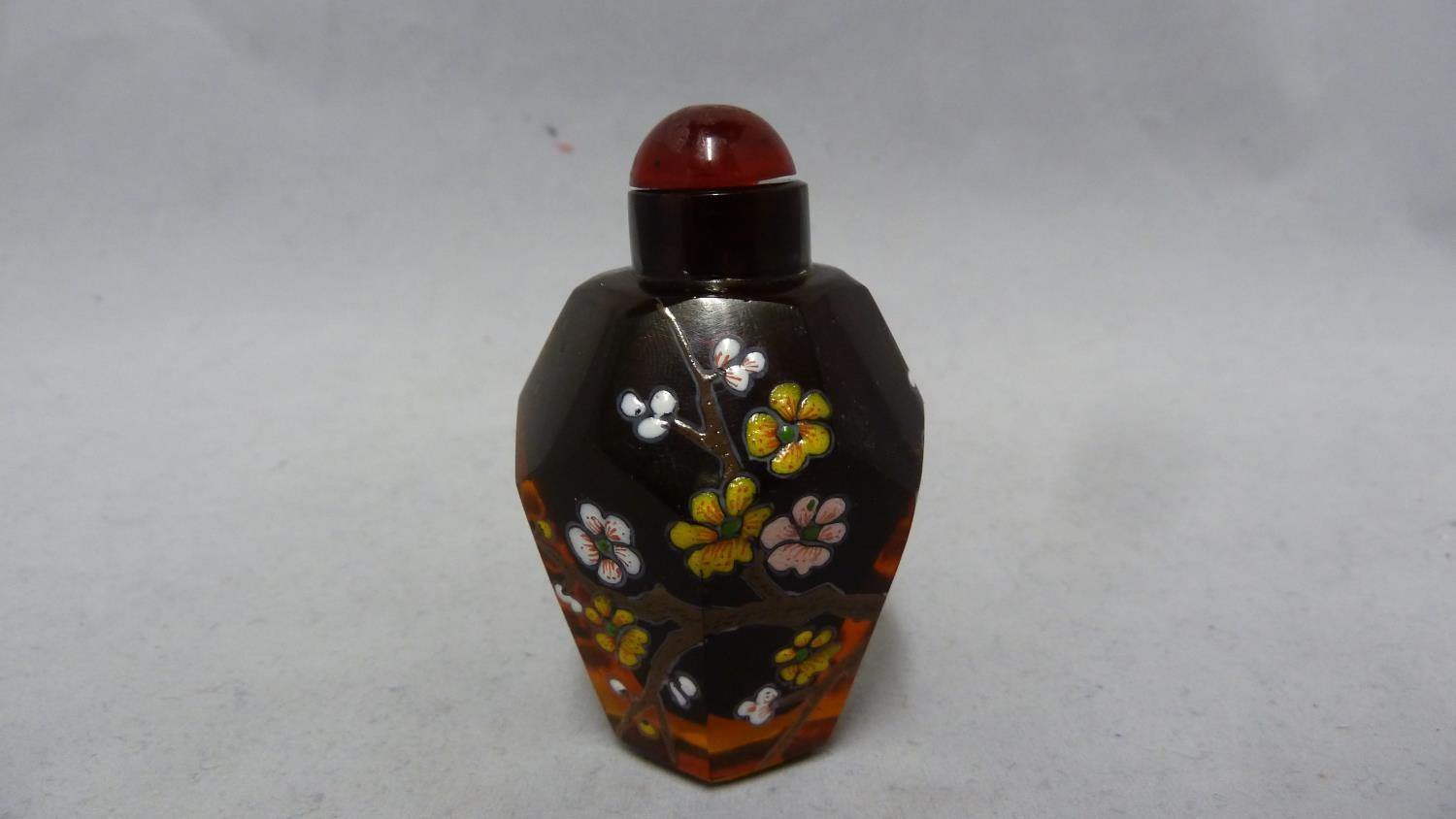 Chinese Glass - a deep amber glass faceted snuff bottle enamelled in polychrome colours with