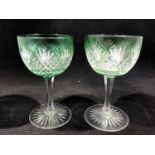 Stevens and Williams - a pair of green overlay wine glasses, the bowls cut through to colourless