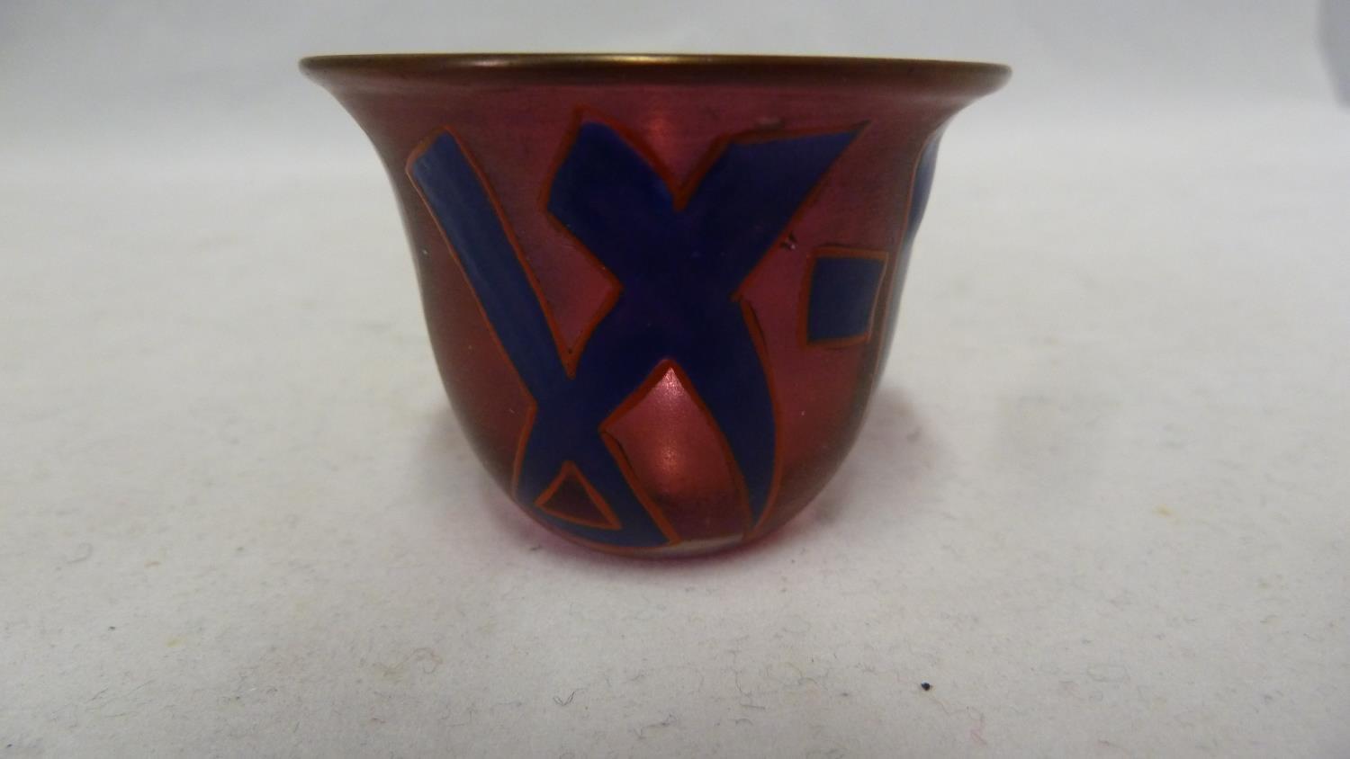 Islamic Glass - a wine cup of ruby colour enamelled with blue script characters outlined in red,