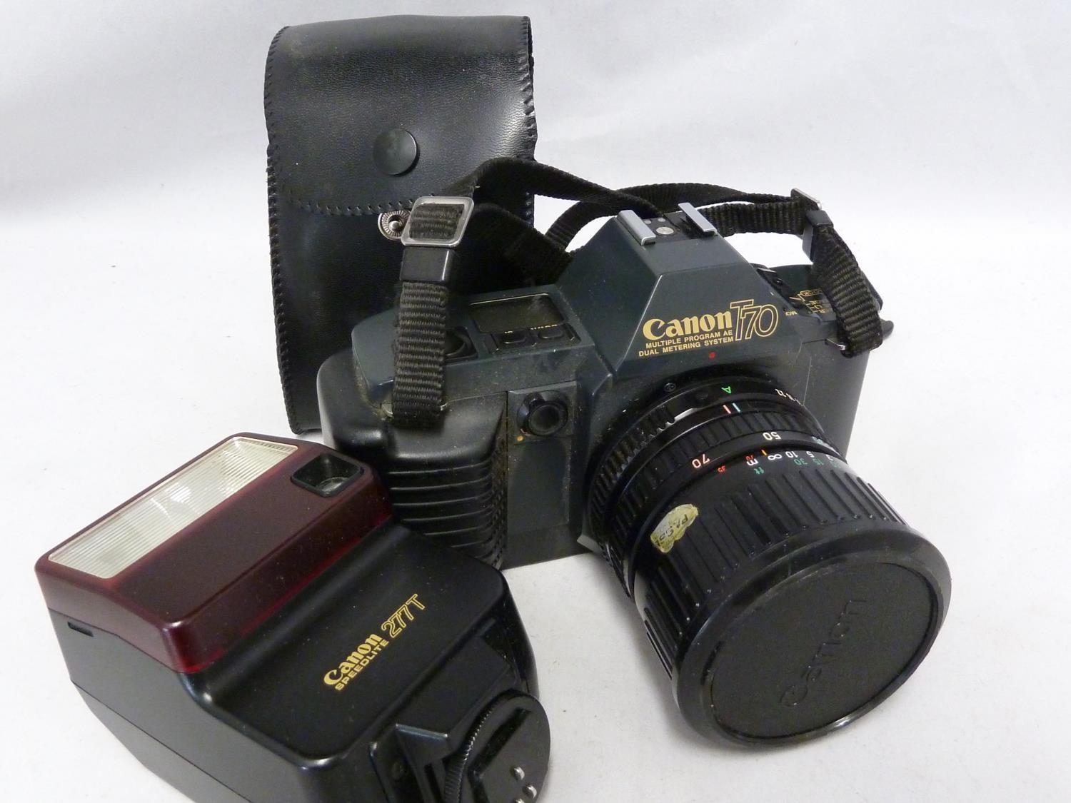 A Canon t70 camera body; a cannon Zoom Lens FD 35-70mm 1:3.6-4.5 with papers; and a Canon Speedlite