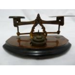 A small size set of brass letter scales and weights, on a mahogany and ebonised finish stepped