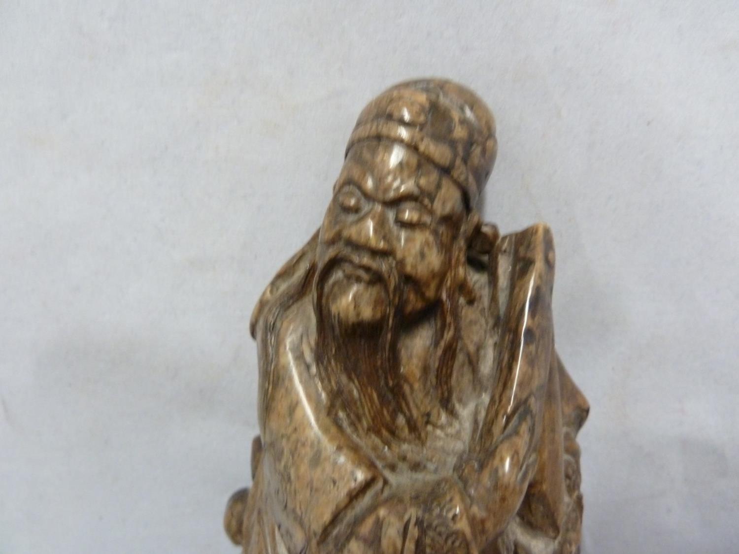 A Chinese carved soapstone figure of an immortal, modelled standing with sceptre and one foot raised - Image 2 of 6