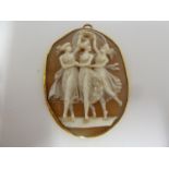 A carved shell cameo pendant, decorated with the Three Graces, within yellow metal oval mount and