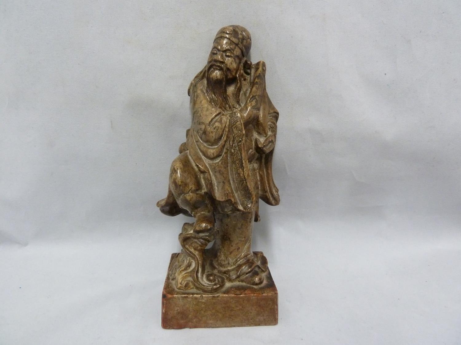 A Chinese carved soapstone figure of an immortal, modelled standing with sceptre and one foot raised