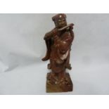 A Chinese carved soapstone figure of an immortal playing a flute, on square section base, 19th