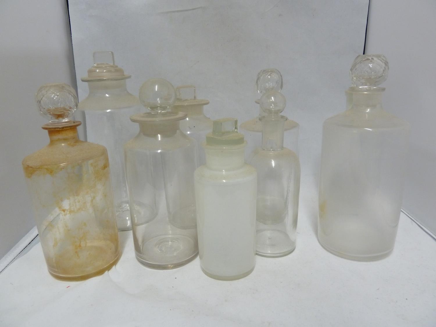 Nine various Chemists/Pharmacy bottles, cylindrical with cut and blown stoppers, 23 cm high and