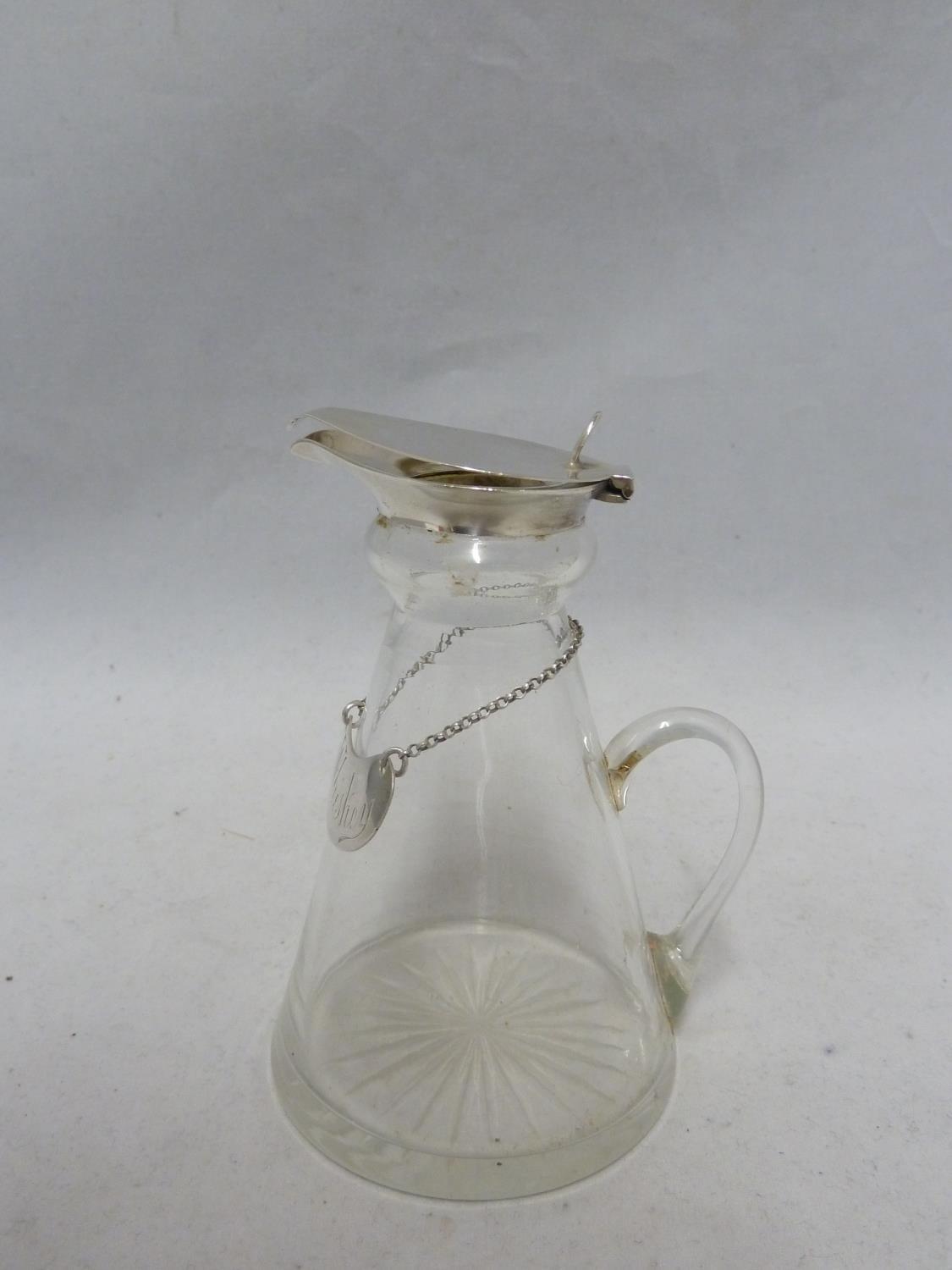 A Whisky noggin, the cut glass flask shaped jug mounted in silver with flip up lid, thumbpiece and
