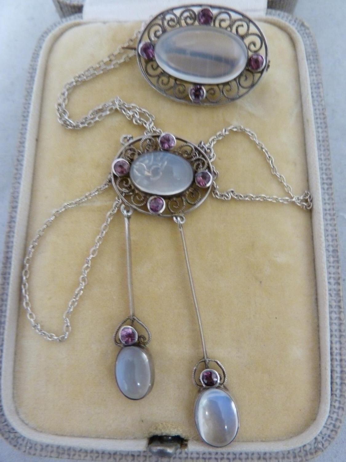 A Belle Epoque pendant and brooch set, the white metal filigree work supporting oval moonstones