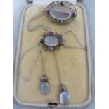 A Belle Epoque pendant and brooch set, the white metal filigree work supporting oval moonstones
