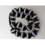 A banded agate necklace, of 23 black and white globular beads, with evenly spaced stripe of white