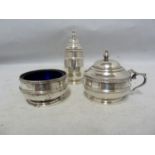 A three piece silver cruet, decorated with beaded and reeded bands beneath vase finials, comprises