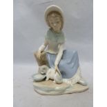 Nao - a porcelain figure of a seated girl feeding a cat from a bowl and leaning on a tree stump,