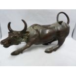 An Indian bronzed metal figure of a bullock, modeled crouching with curled tail, 18.5cm high