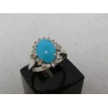 A turquoise and diamond ring, the oval turquoise encircled by 18 round brilliant cut diamonds, set