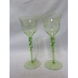 Stourbridge, England - a pair of green uranium glass wine glasses, the bowls engraved with swags and