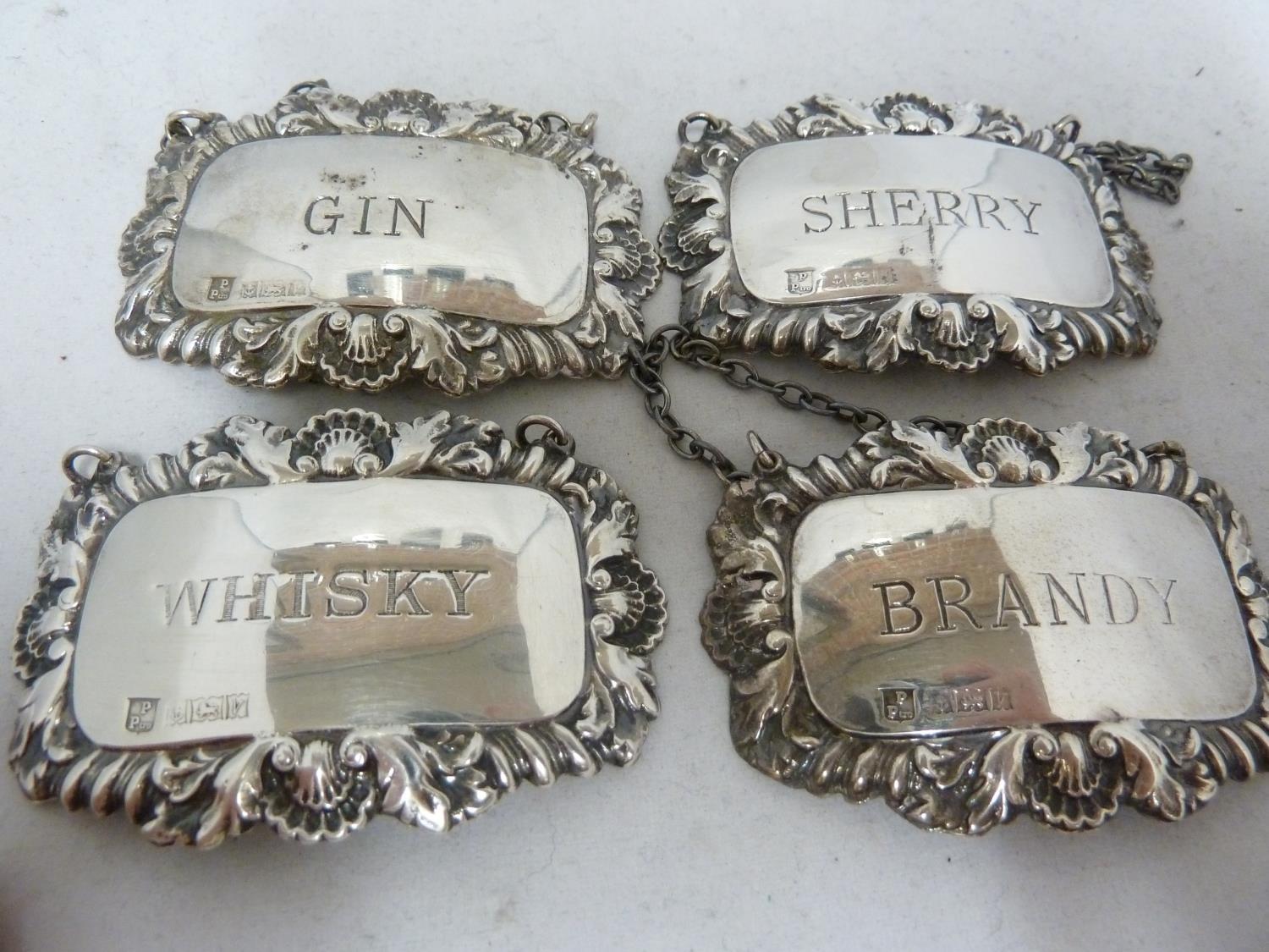 Four silver decanter labels, rectangular with shell and foliate gadrooned frames, marked BRANDY,