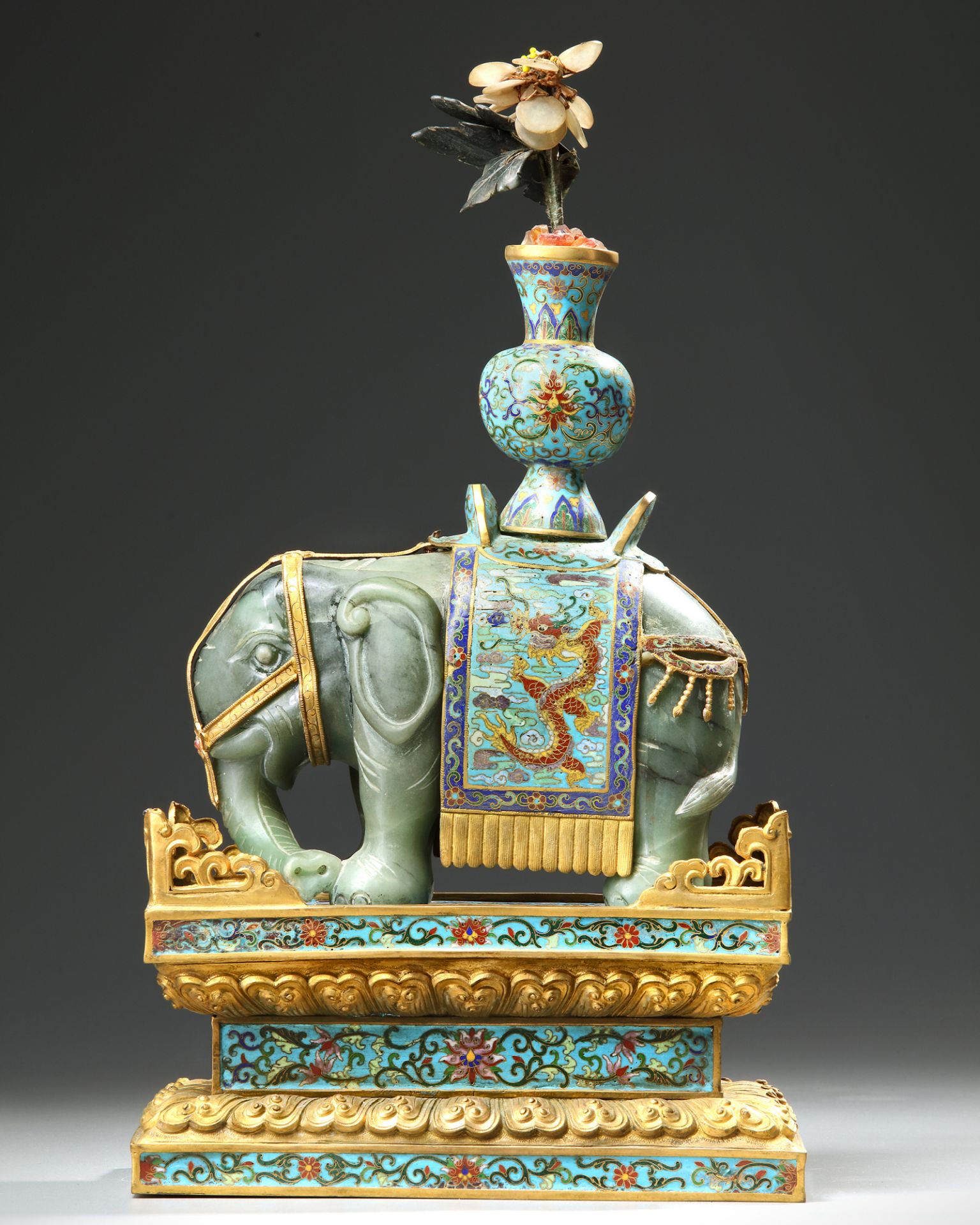 A CHINESE JADE AND CLOISONNÉ CAPARISONED ELEPHANT ON A CLOISONNÉ BASE