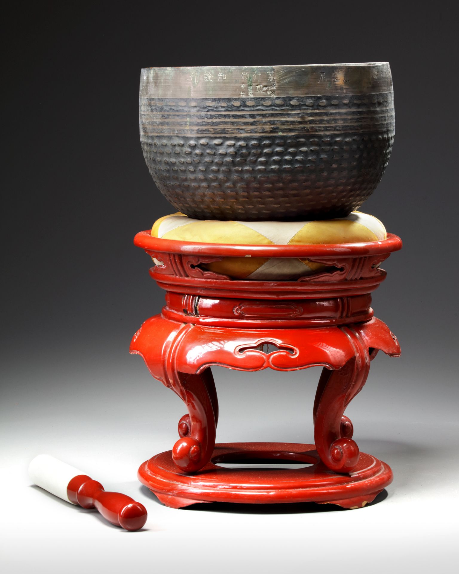 A JAPANESE TEMPLE BELL ON RED LACQUERED STAND WITH PILLOW