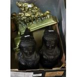 Two black cast metal andirons with bust of a lady, decorative brass scene and a trophy shaped