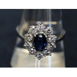 An 18ct white gold sapphire and diamond cluster ring, the oval sapphire surrounded by ten